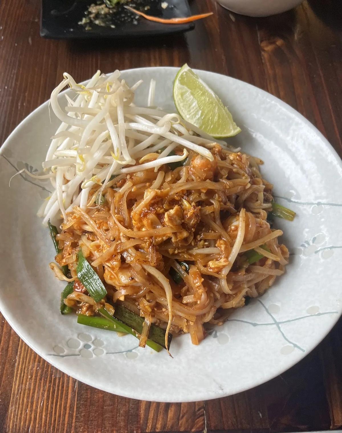 A plate of pad thai with lime and bean sprouts