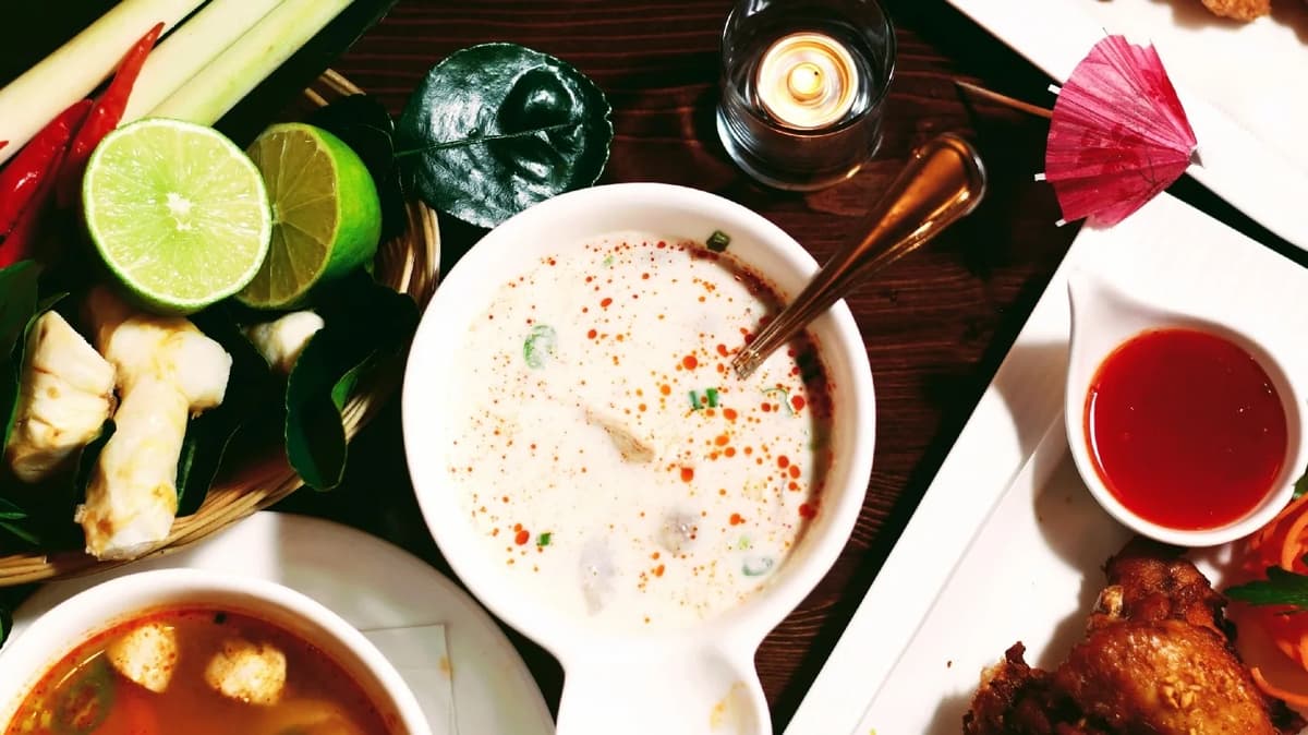 Bowls of soup, curry and lime laid out on a table